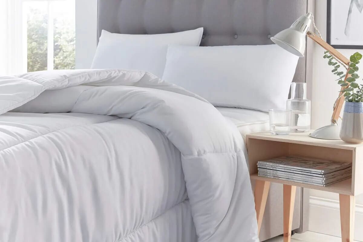 White bedding on a grey divan bed.