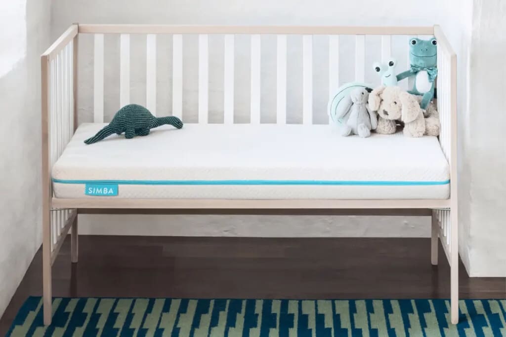 Image of the Simba Cot Mattress on a white cot bed wiht soft toys on top.