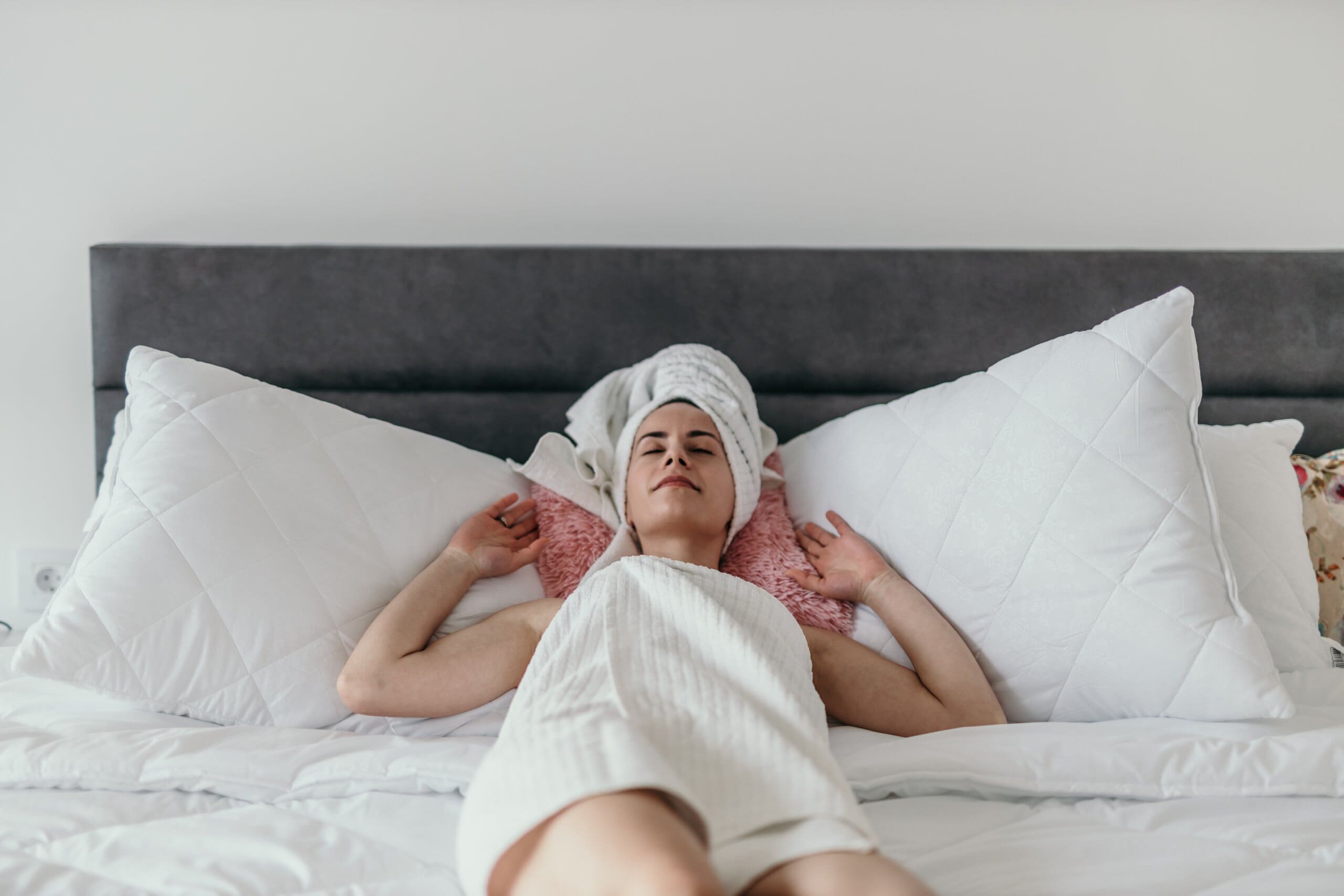 Woman resting on her bed in a towel, ready to sleep without anxiety.