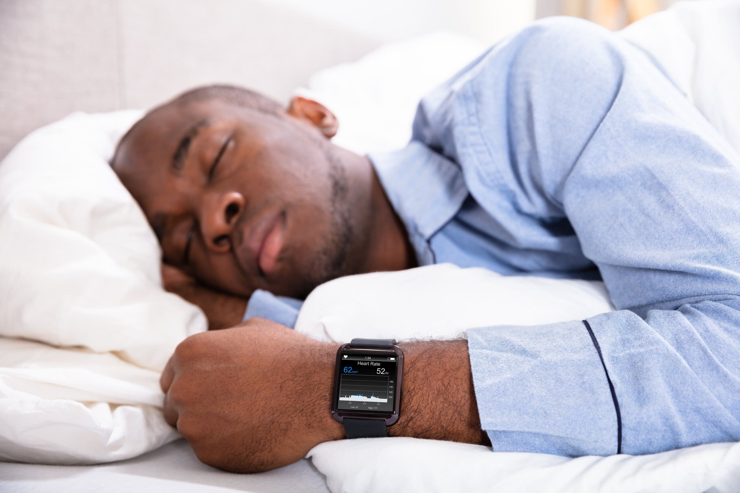 Man sleeping with a smart watching sleep tracker on his wrist.