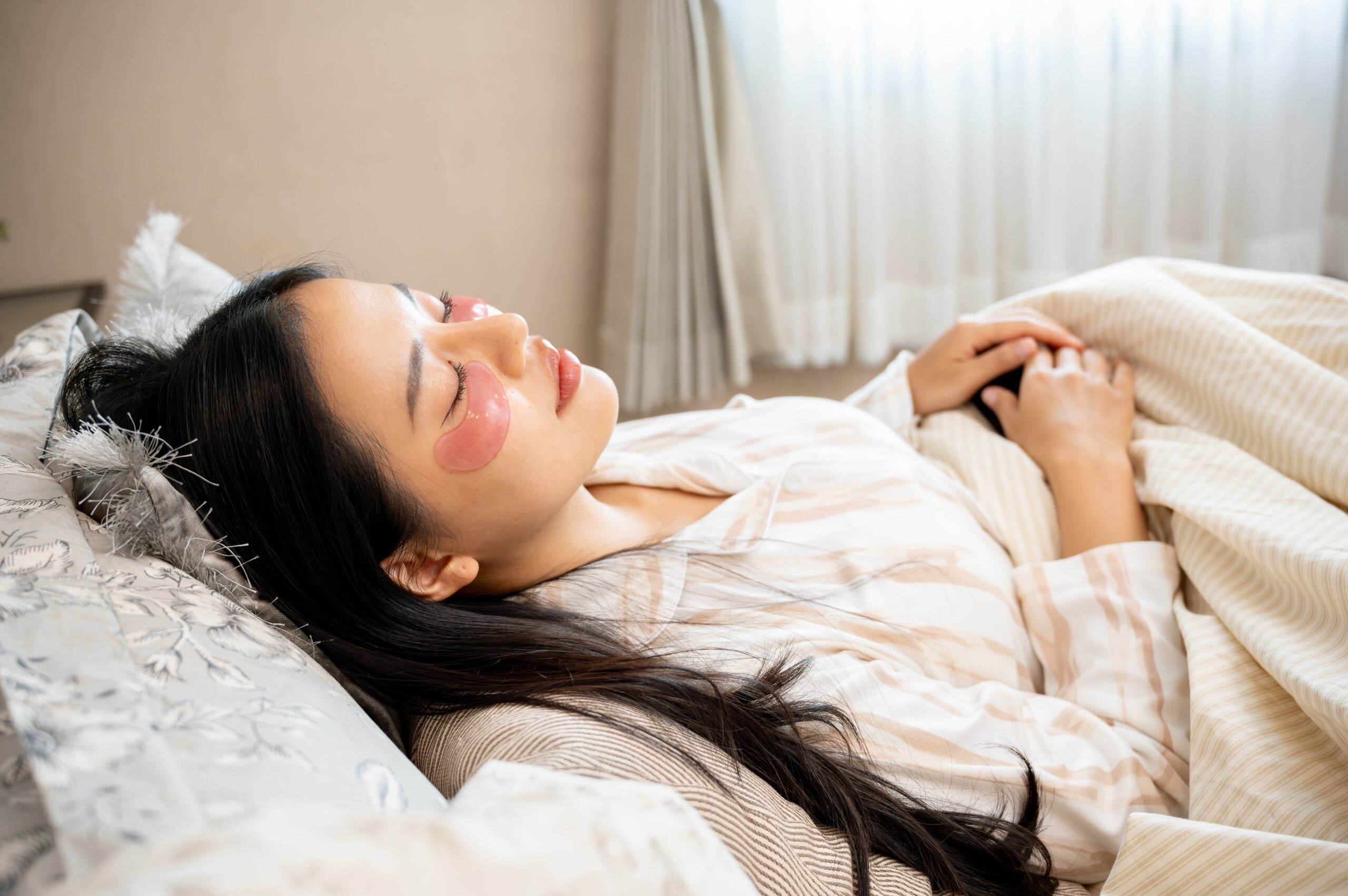 Woman sleeping with hydrating eye patches under her eyes.