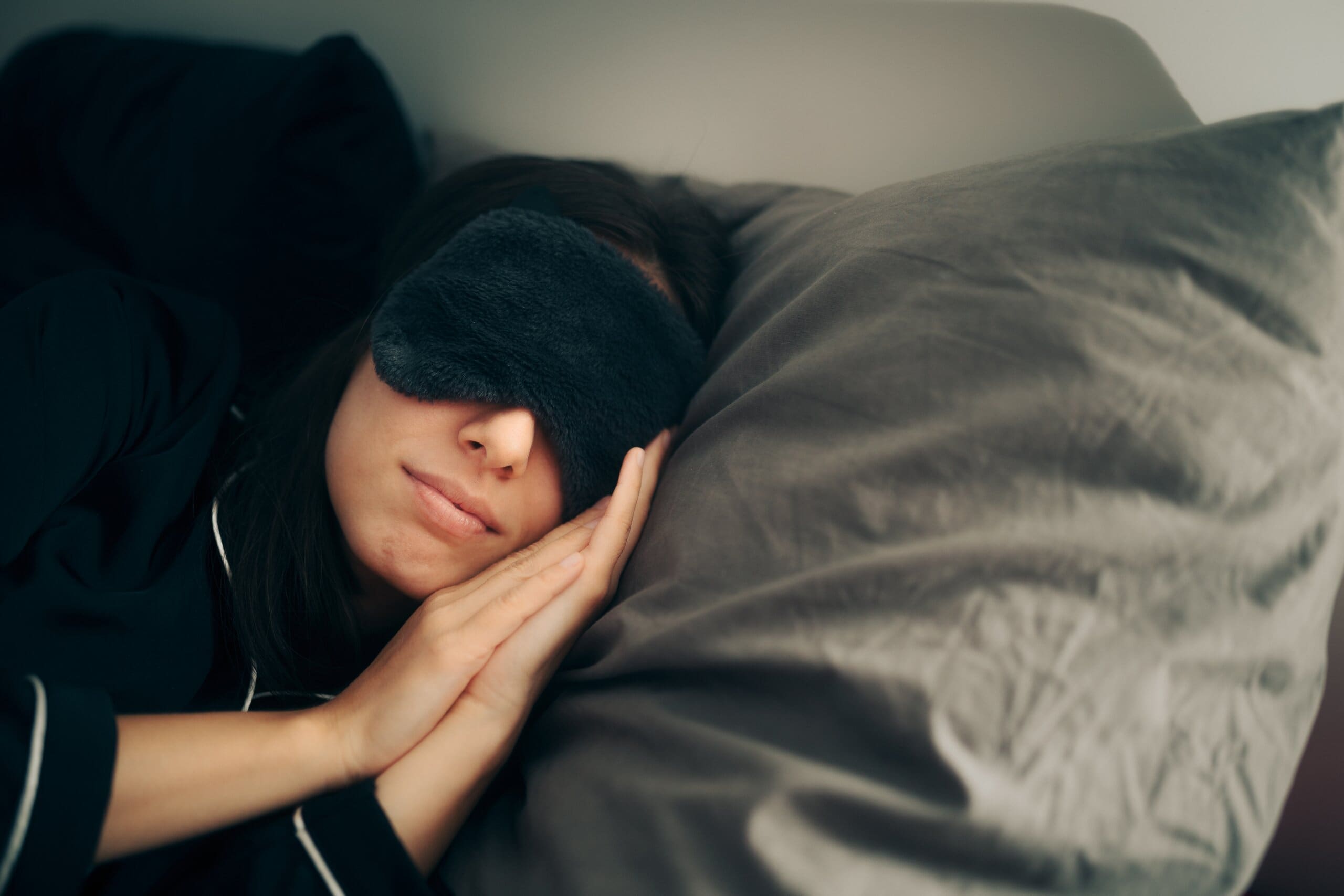 Woman wearing eye mask asleep during a sleep cycle.