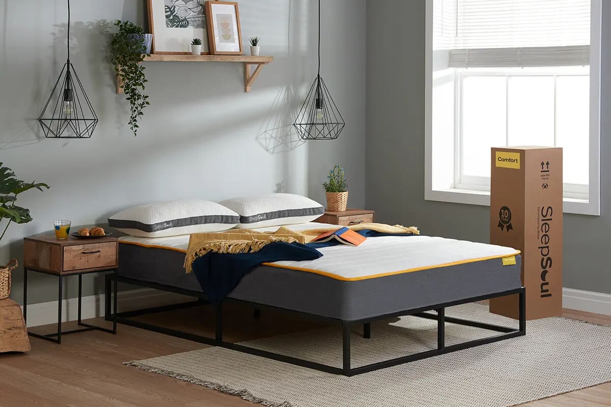 Image of the Sleepsoul comfort mattress on a black low metal bed frame with the mattress box to the side.
