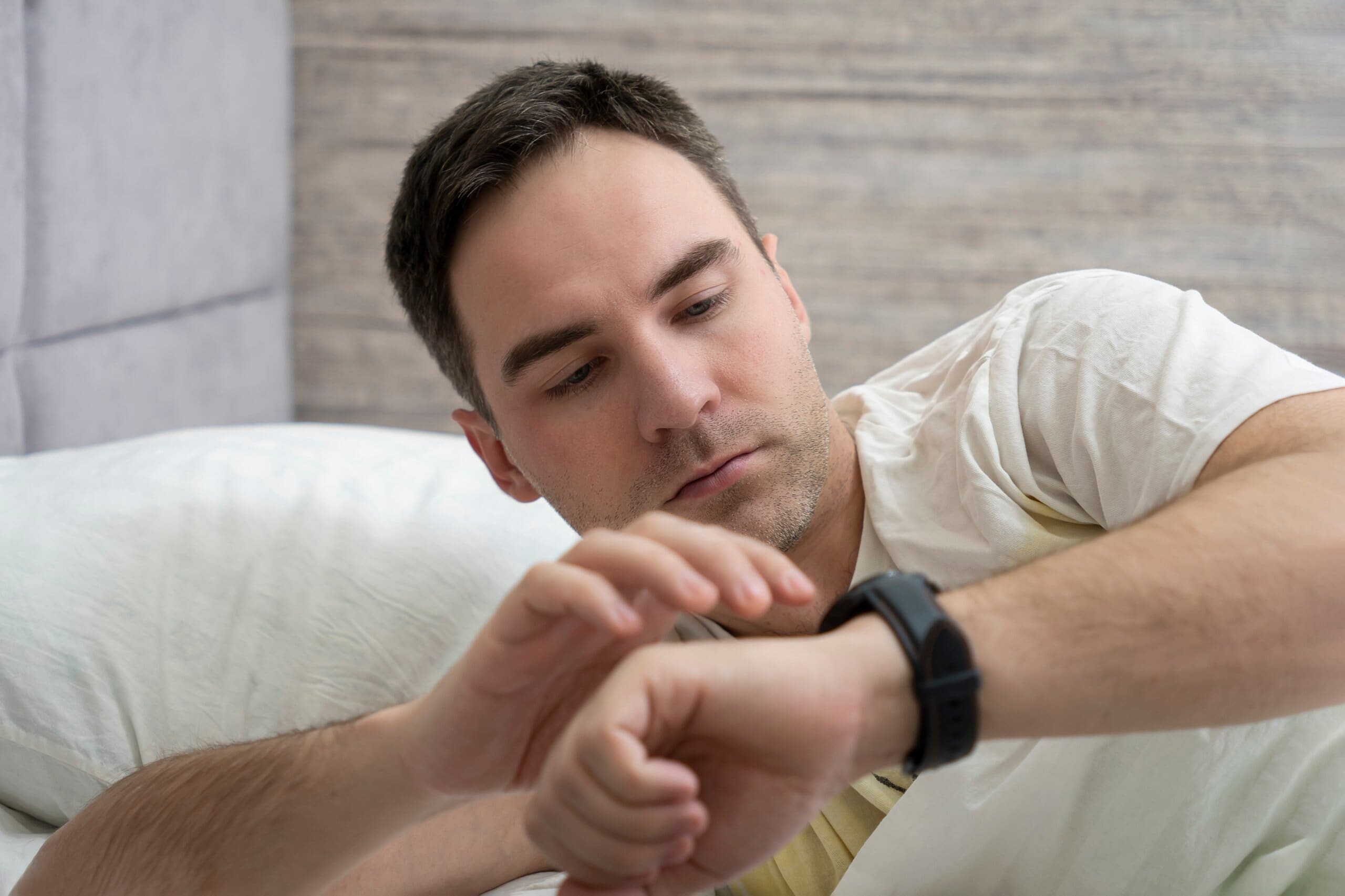 Man checking his smart watch in bed.