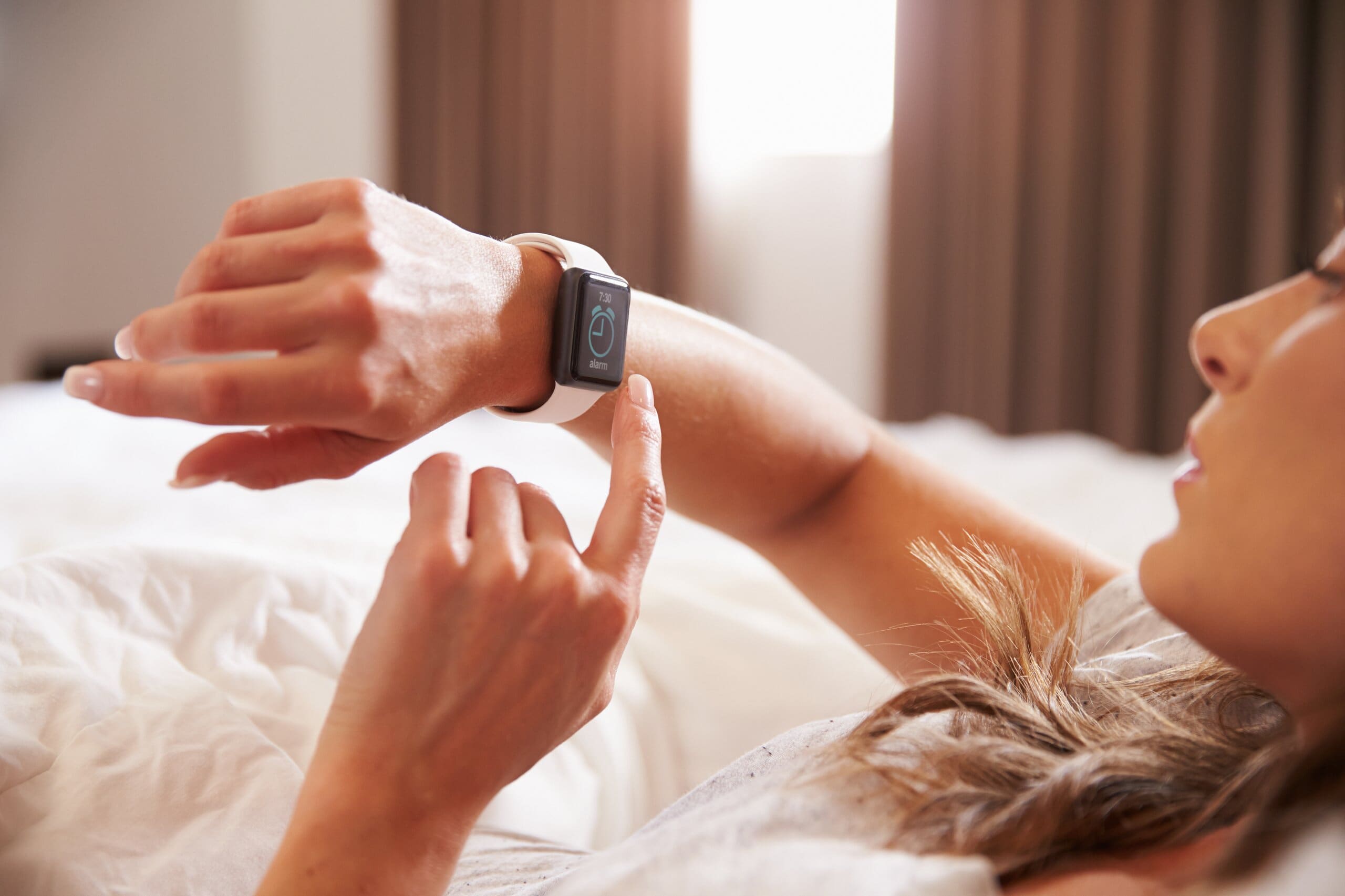 Woman looking at her smart watch in bed.