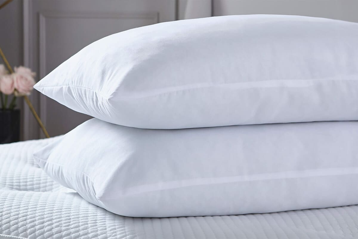 Image of two uncovered pillows on a stripped bed.