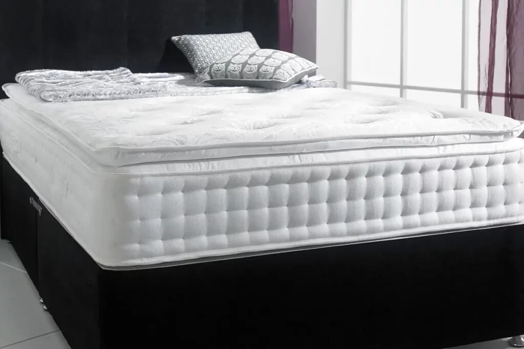 Image of a pillow top mattress with scatter cushions on a divan base.
