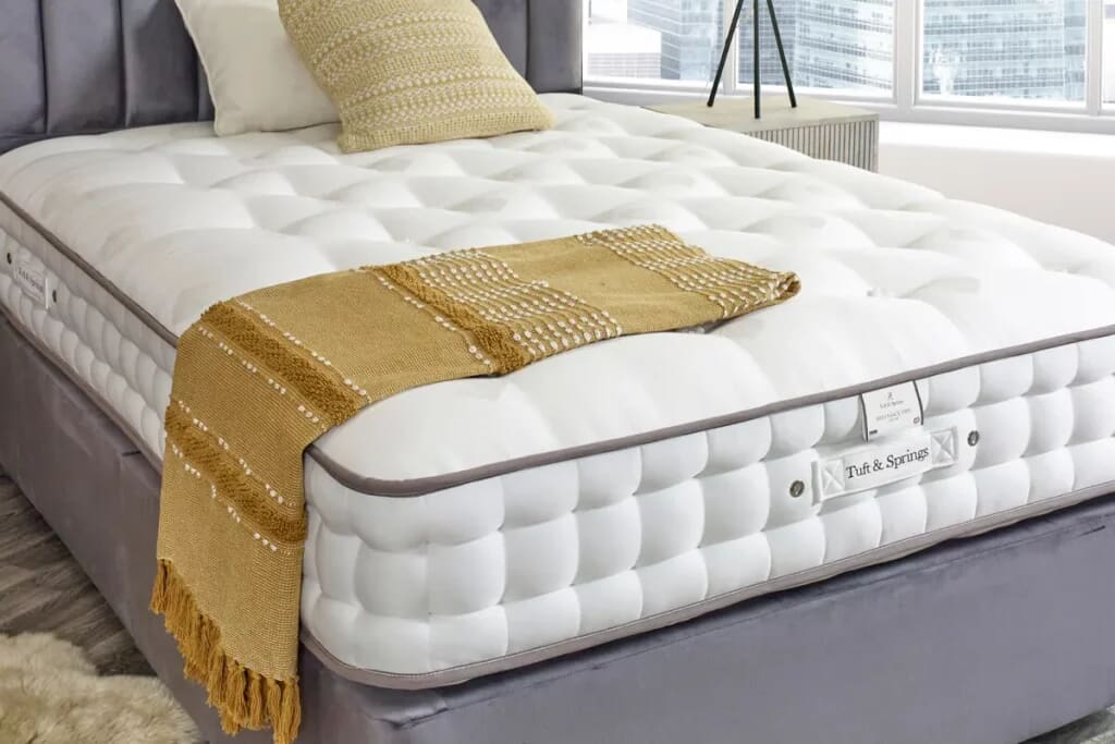 The tuft and springs ortho mattress on a grey divan with yellow accessories.