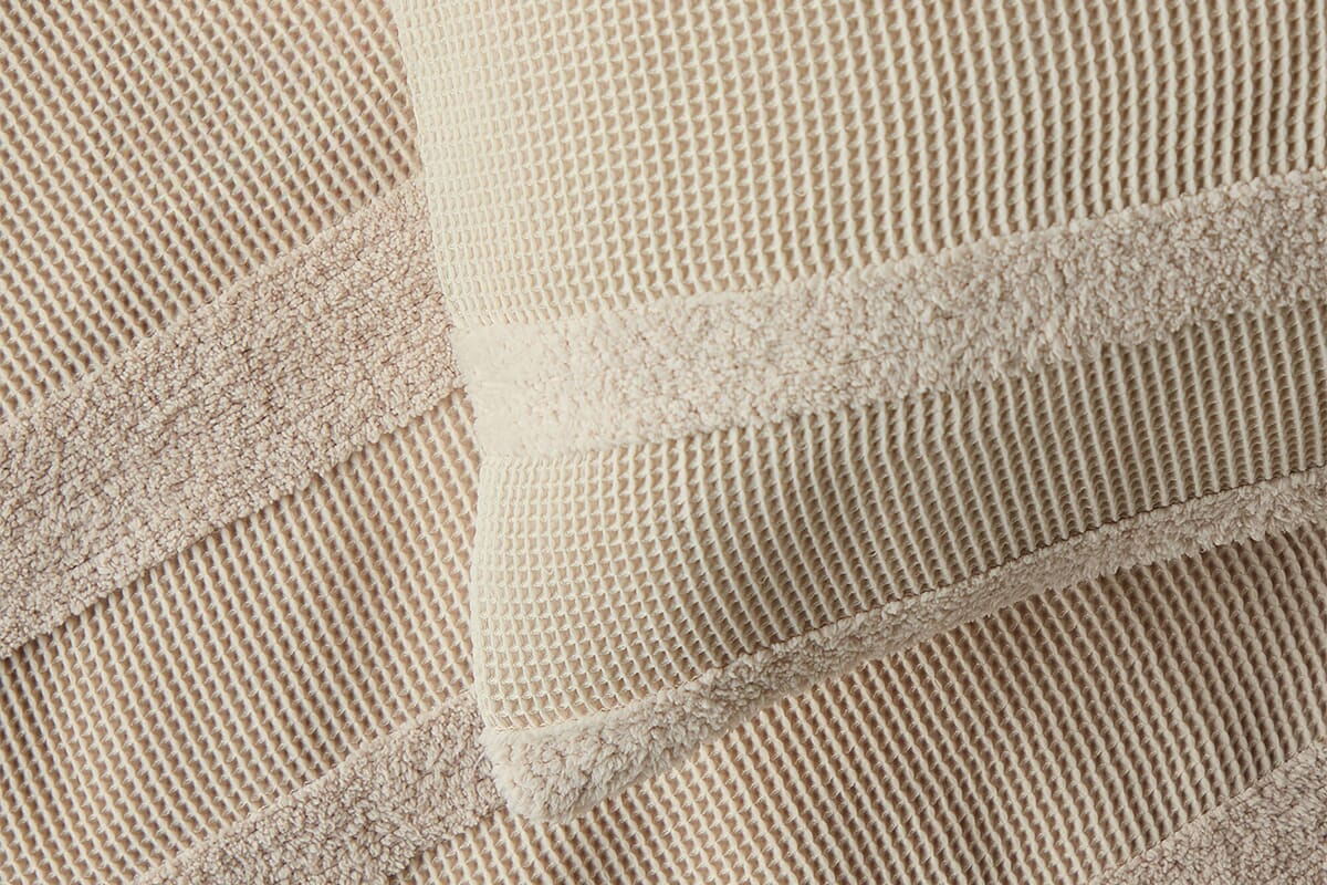 Close up of waffle bedding, including a corner of a pillow.