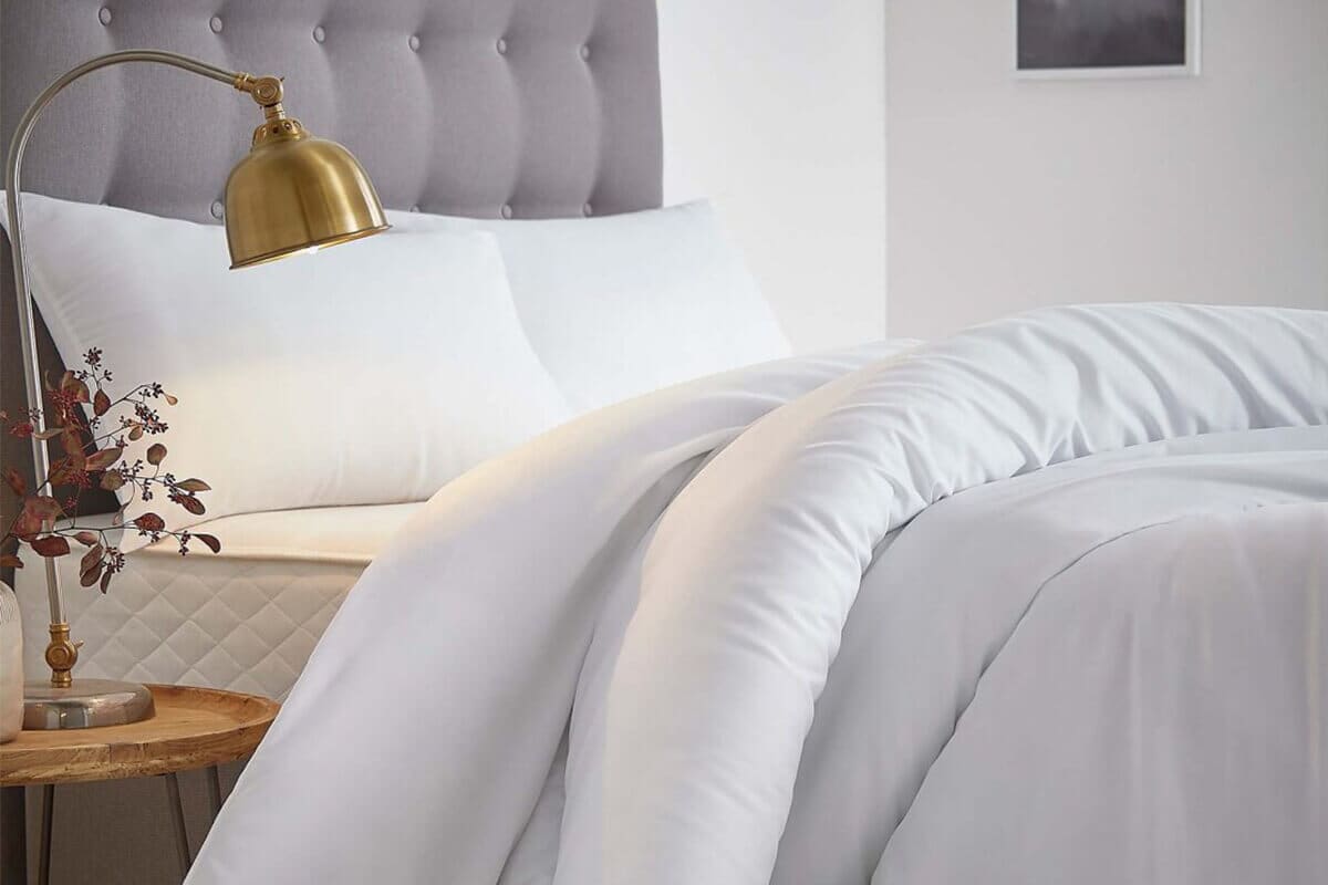 Image of a white bed with the duvet pulled back.