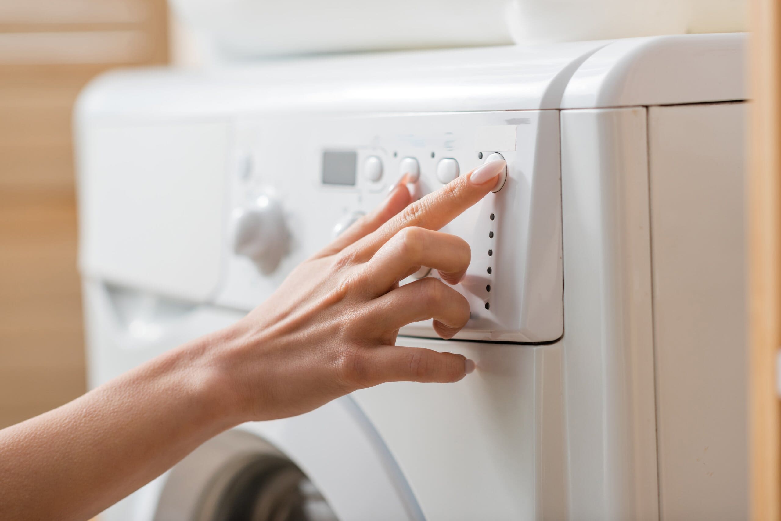 Cropped image of a woman's hand turning a washing machine on.