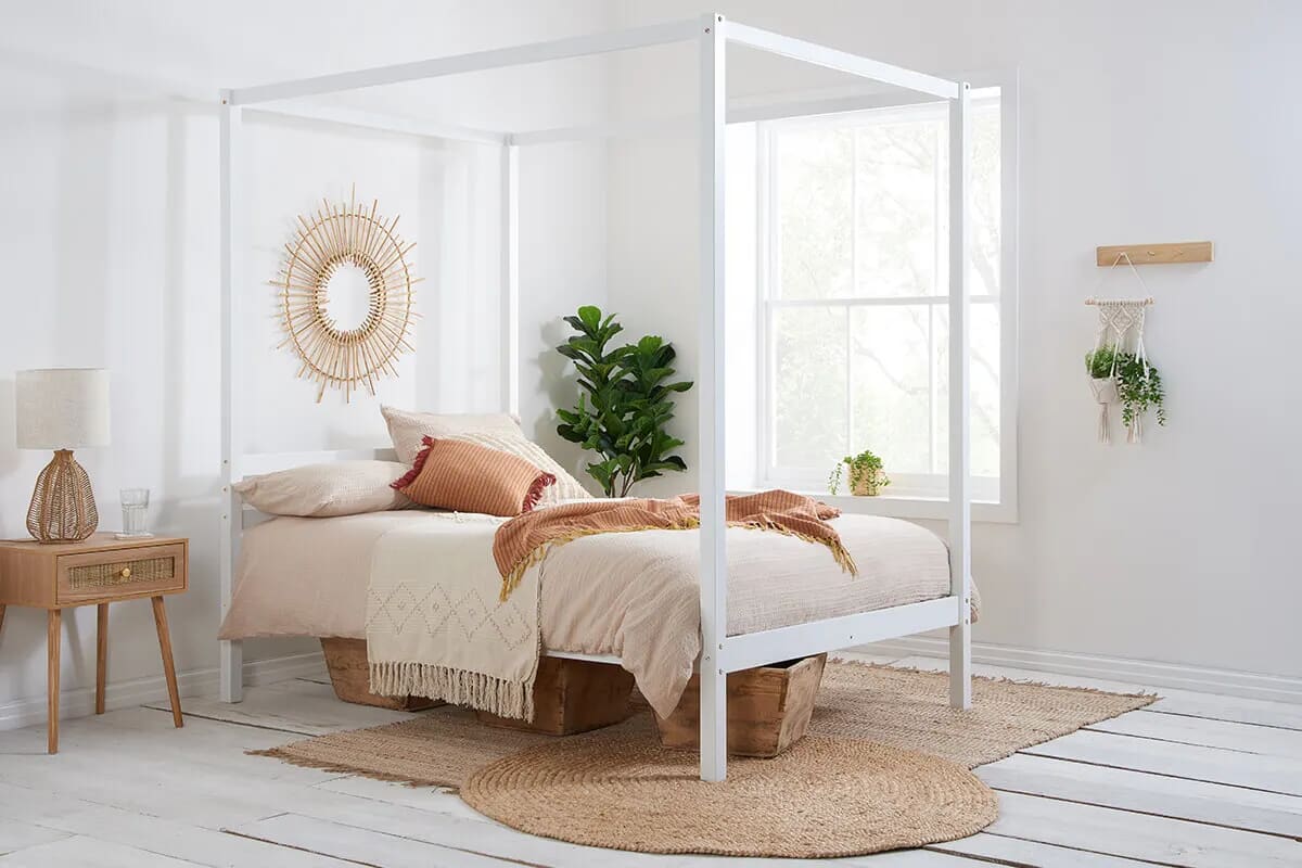 Image of white four poster bed in white boho bedroom.
