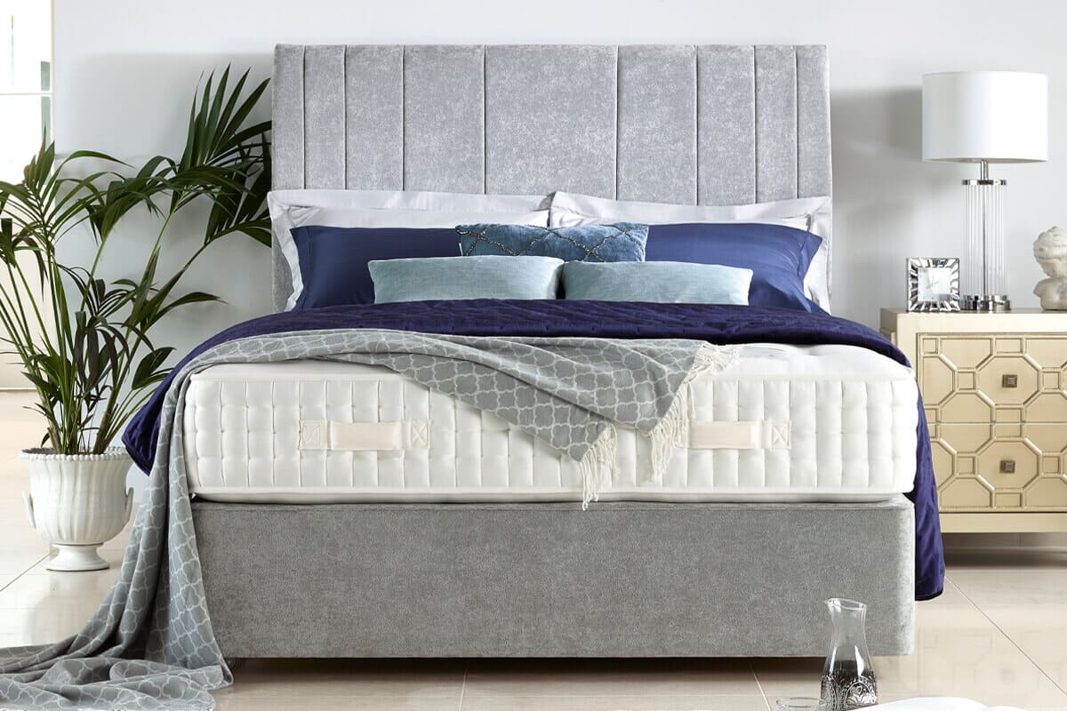 The Harrison Spinks Winchester mattress on a grey divan bed with blue bedding.